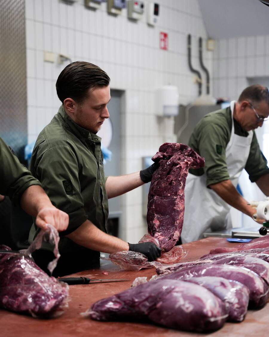 Twee slagers snijden vlees in de werkplaats