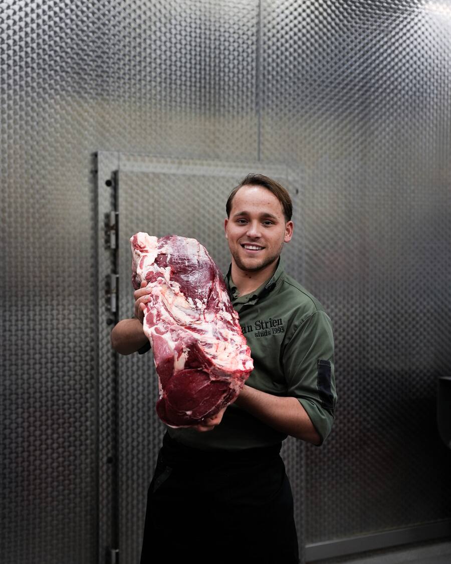 Slager met een groot stuk vlees in de koelcel