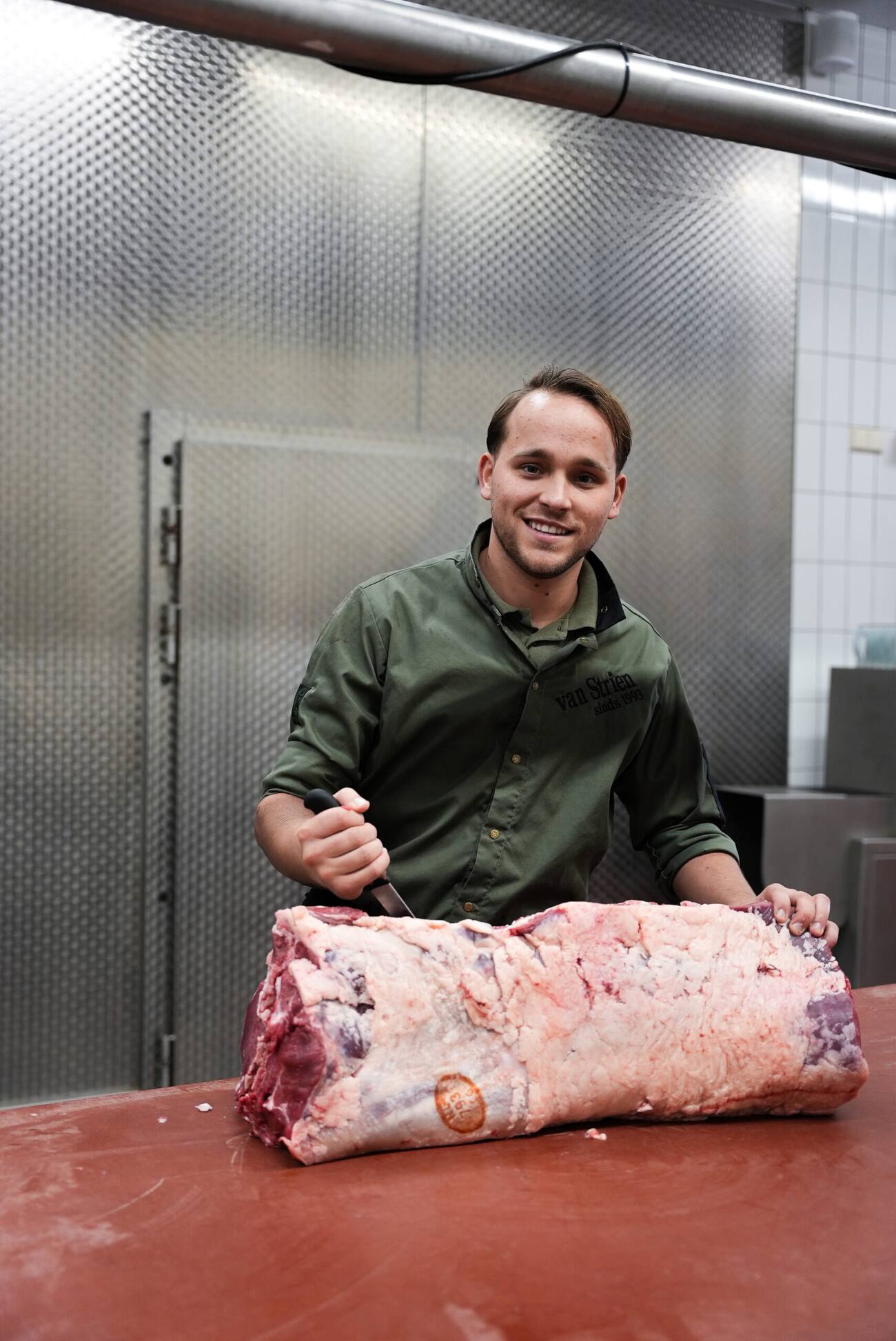 Slager met een groot stuk vlees in de koelcel